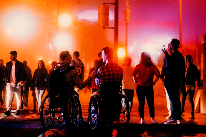 Deux personnes en fauteuil roulant échangent au cœur d’une foule pendant le festival Aupa Pireneas Festival